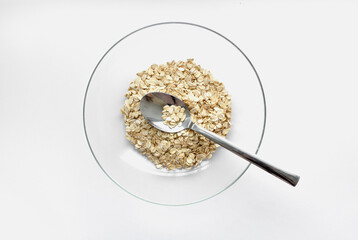 oat cereals in a glass bowl with a spoon on a white background. View from above. Place for text
