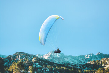 Paraglider flying above the mountains in sunshine