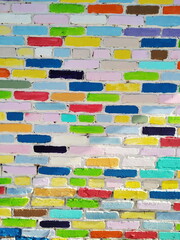 A fragment of a textured creatively decorated brick wall with bricks of different colors