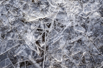 A fragment of broken thin ice from a puddle similar to glass close up