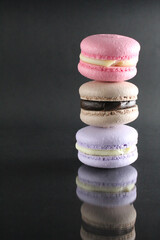 three macaroon brown pink cakes on a black glossy background with a place for text and copyspace