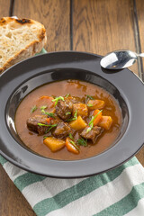 beef stew with bread toast in grey plate on wooden table
