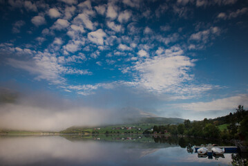 Dawn over the water. Fog over the lake. Fishing boats at the pier. Peace and serenity of the morning 