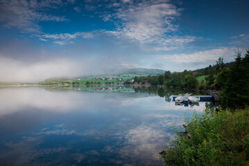 Dawn over the water. Fog over the lake. Fishing boats at the pier. Peace and serenity of the morning 