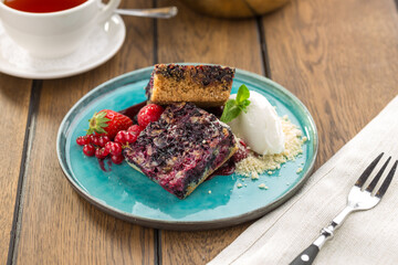 Blueberry crumble with ice cream and cup of tea on wooden table
