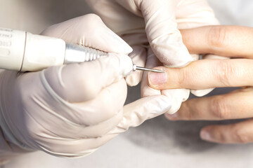 Manicure hand nail care with special tools in a beauty salon by a manicure specialist. Close-up. Space for the text.