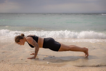 Yoga woman on the beach. Caucasian woman practicing Phalakasana, Plank Pose. Strong body. Healthy...