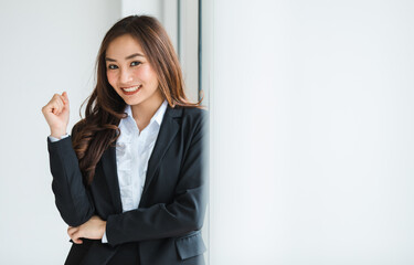 Cute and beautiful brunette Asian female entrepreneur gorgeous looked  in black classy suit standing in office and looking at camera with friendly and positive happy face.