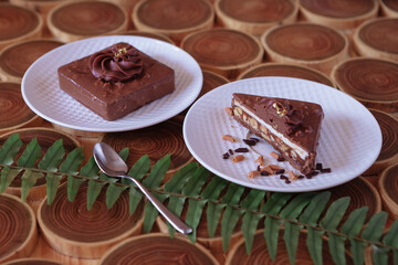chocolate dessert in a cut with filling of caramel, nuts and nougats. The cake is covered with chocolate on a wooded background with a morning natural light