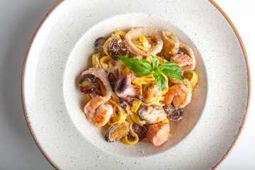 fresh pasta with seafood on a white plate in the studio