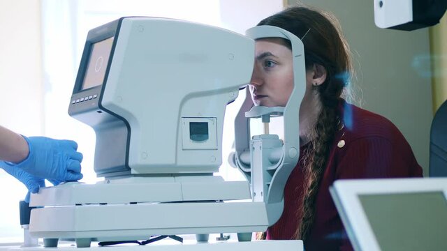 Doctor is inspecting woman's eyes with a medical machine