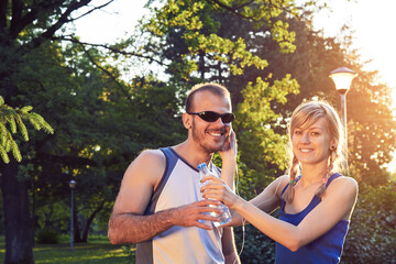 Fototapeta premium Two young sporty man and woman exercising in park at summertime season.