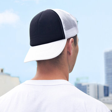 Young Man In A Black And White Trucker Hat And White T-shirt. Trucker Hat Mock Up. Baseball Cap Template