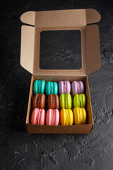 colored fresh macarons in the studio on a black background in a box