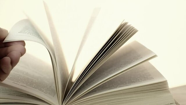 Reading book concept. The hand is leafing through the book. Book pages close up