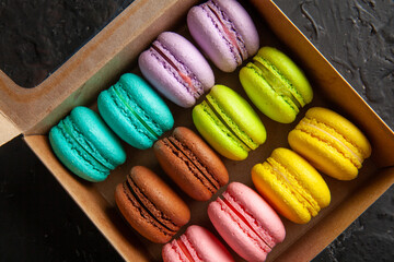 colored fresh macarons in the studio on a black background in a box