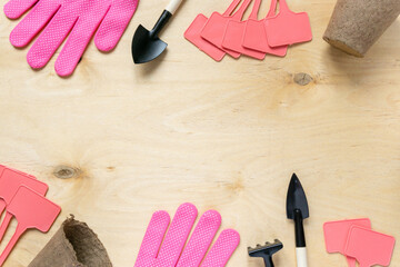 Flat lay of gardening supplies. Tools, peat pots, gloves and seedling plates on wooden background,...