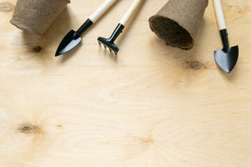Flat lay of gardening supplies. Tools and peat pots on wooden background, space for text