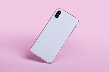 Smartphone in clear silicone case falls down, back view. iPhone X case mockup isolated on pink...