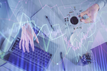 Multi exposure of man's hands typing over computer keyboard and forex graph hologram drawing. Top view. Financial markets concept.