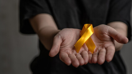 Female hands hold yellow ribbon. Concept of suicide problems and their prevention