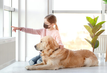 Little girl in mask with golden retriever dog