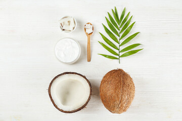 Fototapeta na wymiar Coconut as a food source and cosmetic product. Cracked fruit with a jar of moisturizing cream on wood textured table. Close up, top view, copy space, flat lay, background.