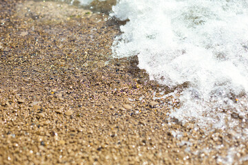 Sea wave on a pebble beach made of small stones. Sea holidays, travel background