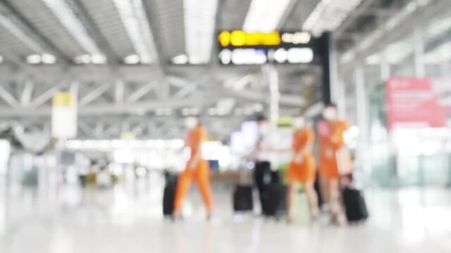 Abstract background, blurred image of stewardesses with suitcases walking in passenger terminal at the airport. 4K Blurred air hostess in international airport, walking with her luggage. 