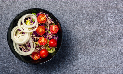 Top view of the healthy colorful salad bowl with tomatoes fresh mixed leaves vegetable in a dish on cement stone table background, Health salad snack diet food weight loss concept