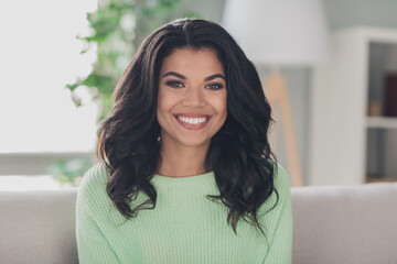 Portrait of attractive gorgeous cheerful girl sitting on couch staying in flat apartment indoor