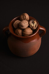Open and closed walnuts inside an old stewpan against black background