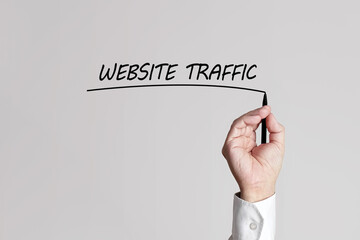 Obraz na płótnie Canvas Businessman hand with pen underlines the words website traffic on a gray background