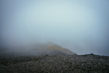Dark atmospheric minimalist foggy landscape on edge of abyss in highlands. Dangerous mountains and...