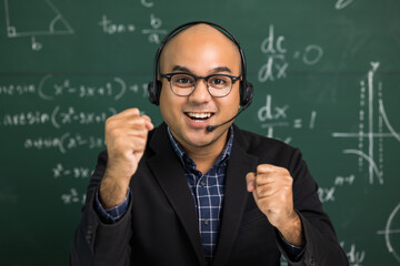 Indian young teacher man looking at camera sitting teaching online video conference live stream. Asian teacher wearing headset teaching class webinar online for students learning.