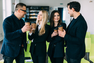Successful young business people are talking and smiling during the coffee break in office