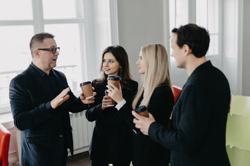 Successful young business people are talking and smiling during the coffee break in office