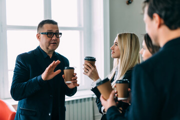 Young business people chatting and drinking coffee at a conference in the office