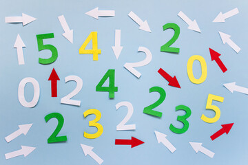 Random arrangement of many colorful numbers and arrows on blue paper.