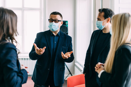 People vs covid. Young business company manager and team of responsible employees care about clients and coworkers wearing protective face masks in office due to the current epidemiological situation