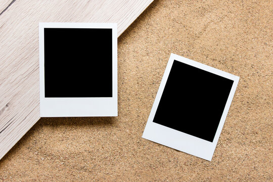 Two polaroid photos cards with blank copy space on wood and real sand background.