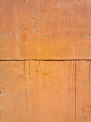 texture of old painted rusty Orange wall or garage door with peeling and cracked paint and corrosion