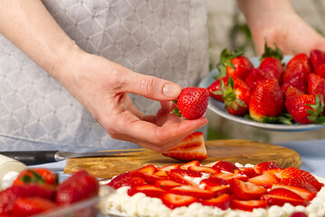 chef decorating delicious dessert with fresh strawberry, strawberry cake. Female holding, selecting strawberry for strawberry cake.