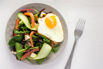 Fresh organic mesclun mix salad with cucumber, mozzarella and salmon, scrambled eggs, delicious hearty breakfast