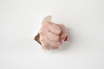 Tightly clenched fist through hole in white paper