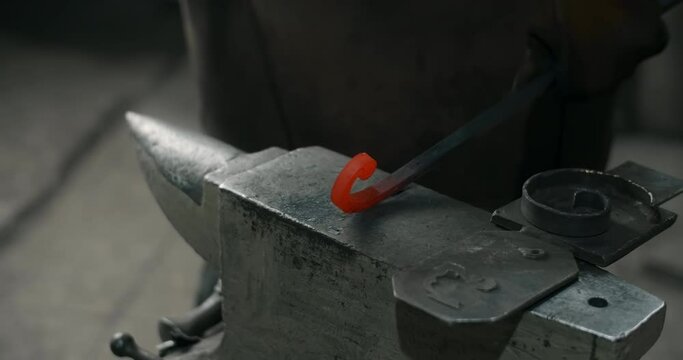 Blacksmith hits with a hammer and shapes the red-hot metal on the anvil, blacksmith craft, forged metal, 4k 60p Prores HQ