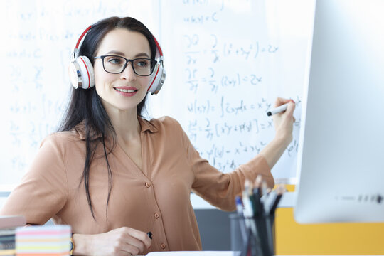 Woman teacher with headphones conducts online math class