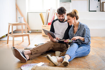 Mid adults couple planning with tablet indoors at home, relocation and diy concept.