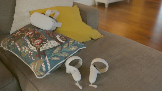 Virtual reality headset and controllers sitting on a couch in a living room.