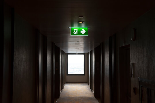 Illuminated green light emergency exit sign in public building for emergency accident and fire evacuation case, green exit light in the building	